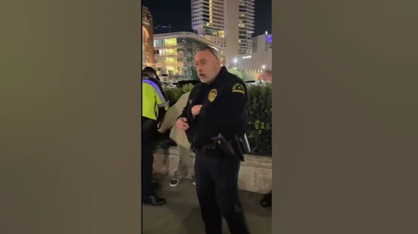 A screenshot of a video showing a Dallas police officer handcuffing two street preachers near American Airlines Center in Dallas, Texas, on Dec. 18, 2025.