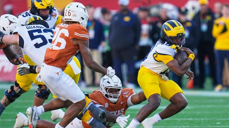 Michigan quarterback Bryce Underwood, right, scrambles for yardage as he...