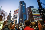 Demonstrators carry signs at the corner of Commerce and Harwood Streets during a 'No War...