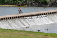 A cyclist rides across a levee in the Trinity River, Wednesday, March 26, 2025, in Fort Worth.