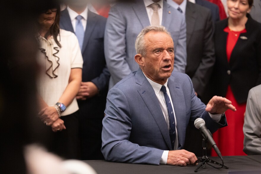 An older white man in a blue suit speaks during a press conference.