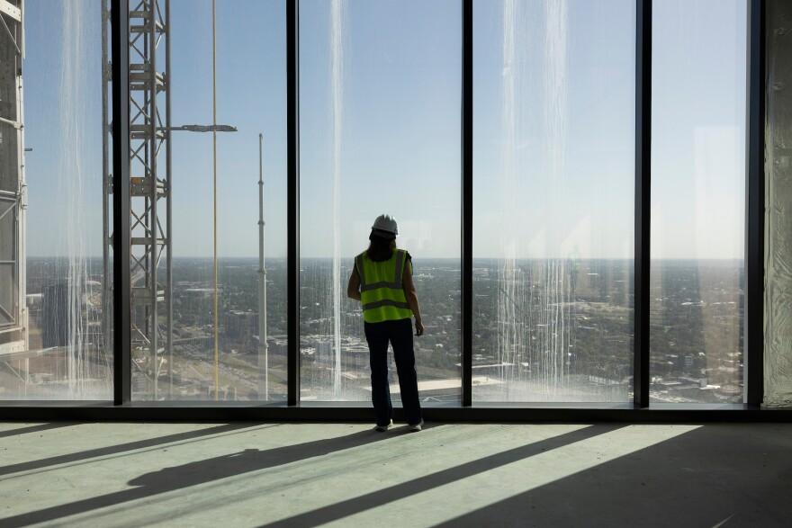 A woman looks out the windows of a floor in the Waterline building in downtown Austin, TX on Thursday, July 31, 2025. The Waterline building is currently the tallest building in Texas. Lorianne Willett/KUT News