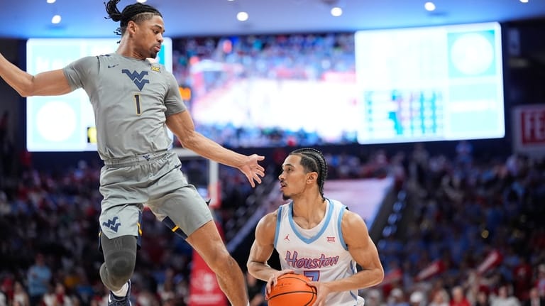 West Virginia's Jasper Floyd (1) defends against Houston's Milos Uzan...