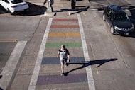 A pedestrian crosses a rainbow painted crosswalk at Cedar Springs Road and Throckmorton...