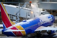 A worker sprays deicing fluid on a Southwest Airlines plane at the gates of Dallas Love...