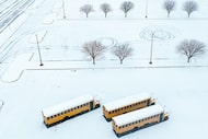 School buses sit idle in the snow at Plano Senior High School on Thursday, Jan. 9, 2025, in...