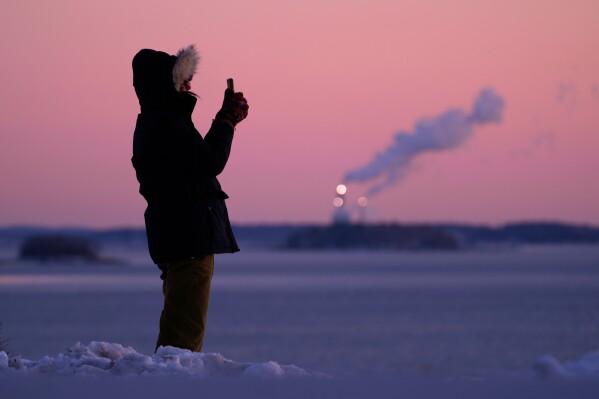 Emma Nadeau, of North Yarmouth, Maine, photographs the pre-dawn scene overlooking Casco Bay on a 1-degree F. morning, Saturday, Jan. 24, 2026, in Portland, Maine. (AP Photo/Robert F. Bukaty)
