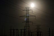 The sun begins to set behind powerlines and a power station, Wednesday, Jan. 21, 2026, in...