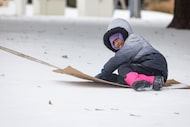 Kaylee Maratas, 8, is pulled around on a makeshift sled in the snow by her father at Exall...