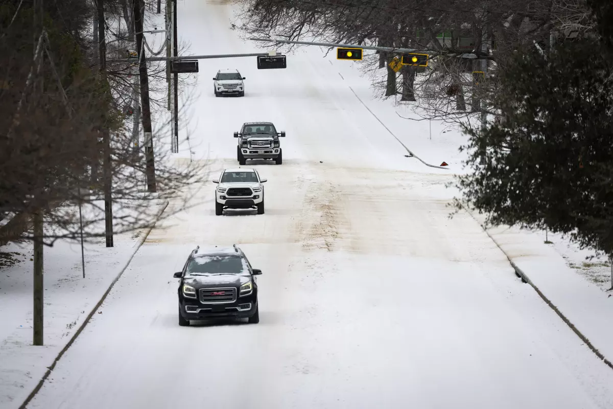Cars navigate icy roads after Winter Storm Fern passes the area Sunday, Jan. 25, 2026, in Dallas.