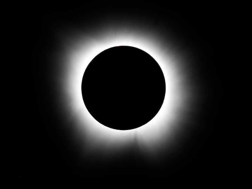 Solar flares from the sun radiate out from behind the moon during a total solar eclipse in...