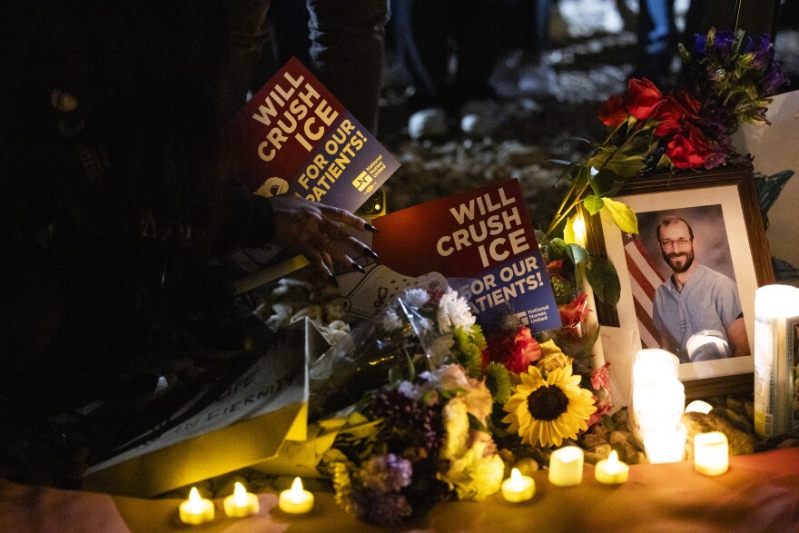 Signs reading 'Will crush ICE for our patients" sit alongside candles, flowers and a photo of a man. 