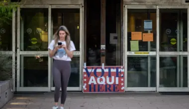 A person walks away from a building with a sign out front that says, "Vote Aqui Here."