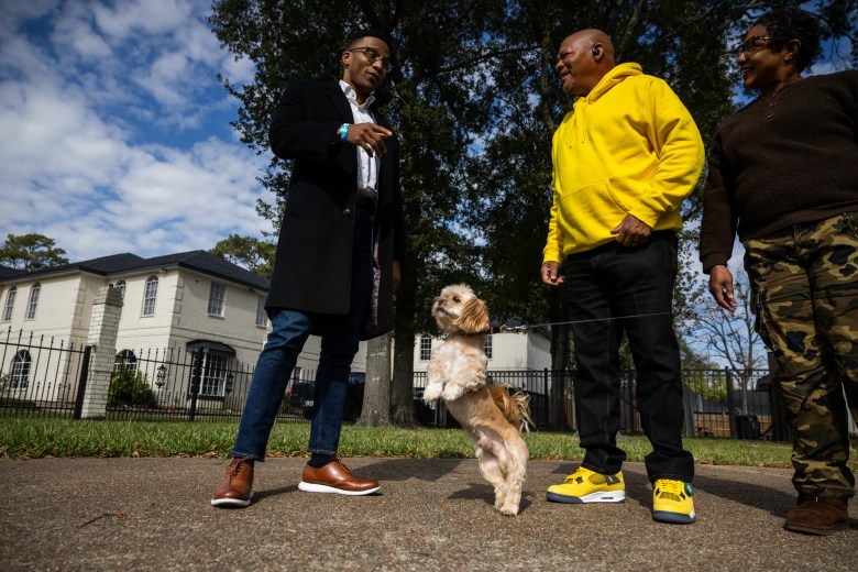 Christian Menefee, candidate for Texas’s 18th Congressional District, talks with Charles, at center, and Tiffany Crowder as their dog, Cujo, leaps in the air on Jan. 17, 2026, in Houston.