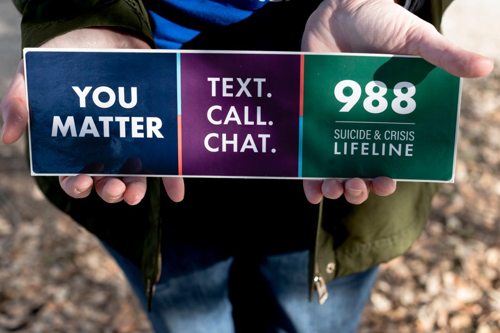 Hewitt holds a sticker for the new digits for Vibrant Emotional Health, the administer of the 988 Lifeline.