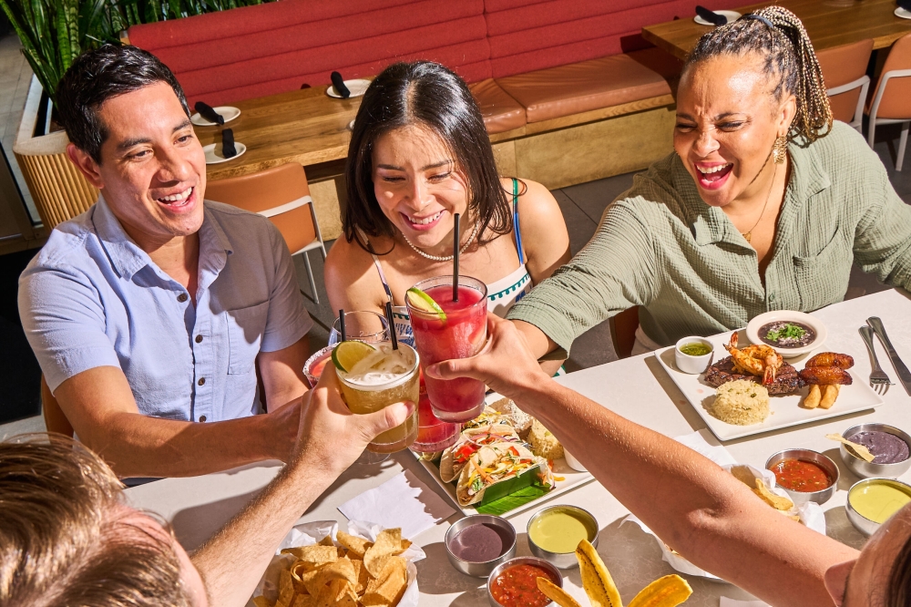 A group of diners cheers over platters of food