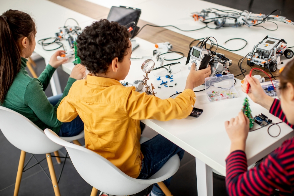 A group of kids programming electric toys and robots at robotics classroom