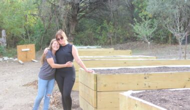 From left, Brandy Gerstner stands with her daughter Ashlee Willis beside the new planter boxes they rebuilt months after catastrophic July flooding destroyed their homes and seasoning business. (Haley McLeod/Community Impact)