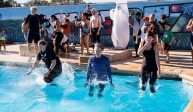 people wearing clothes jumping into a swimming pool