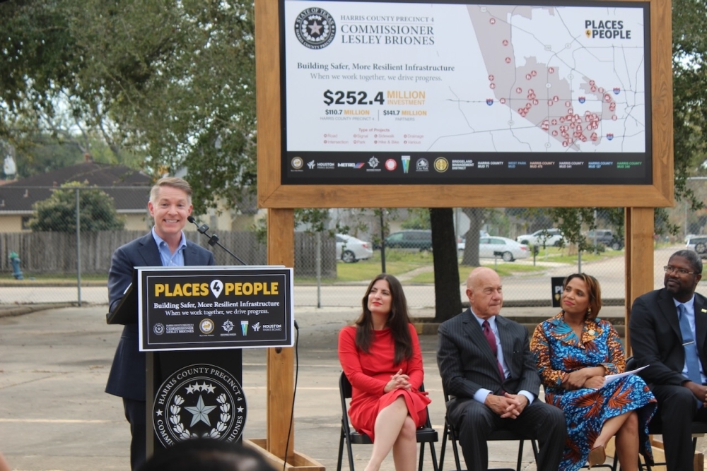 A man speaks at a podium with government officials
