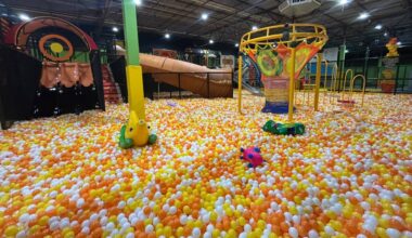 Foam pit featuring yellow, orange and white foam pieces as well as structures for aiming propelled foam pieces at.