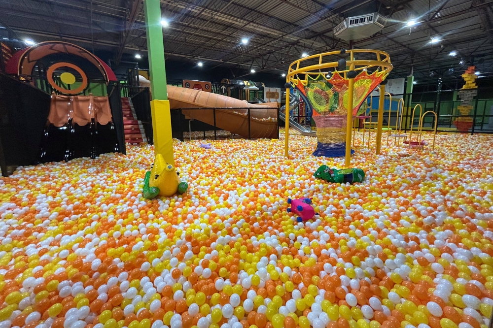 Foam pit featuring yellow, orange and white foam pieces as well as structures for aiming propelled foam pieces at.