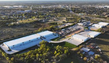 An ariel view of Tower Business Park comprised of a large white building with four smaller while buildings surrounded by trees.