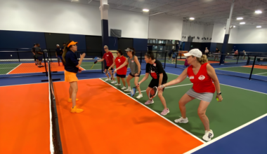 Pickleball enthusiasts playing on state-of-the-art indoor courts at Dill Dinkers Plano, featuring CushionX flooring for reduced joint strain, a climate-controlled environment, and expert coaching for beginners to competitive players.