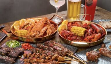 two Cajun seafood boils, a plate of skewers, and various alcoholic drinks on a table