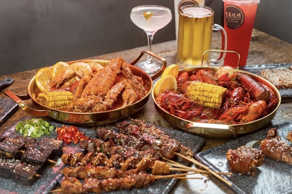 two Cajun seafood boils, a plate of skewers, and various alcoholic drinks on a table