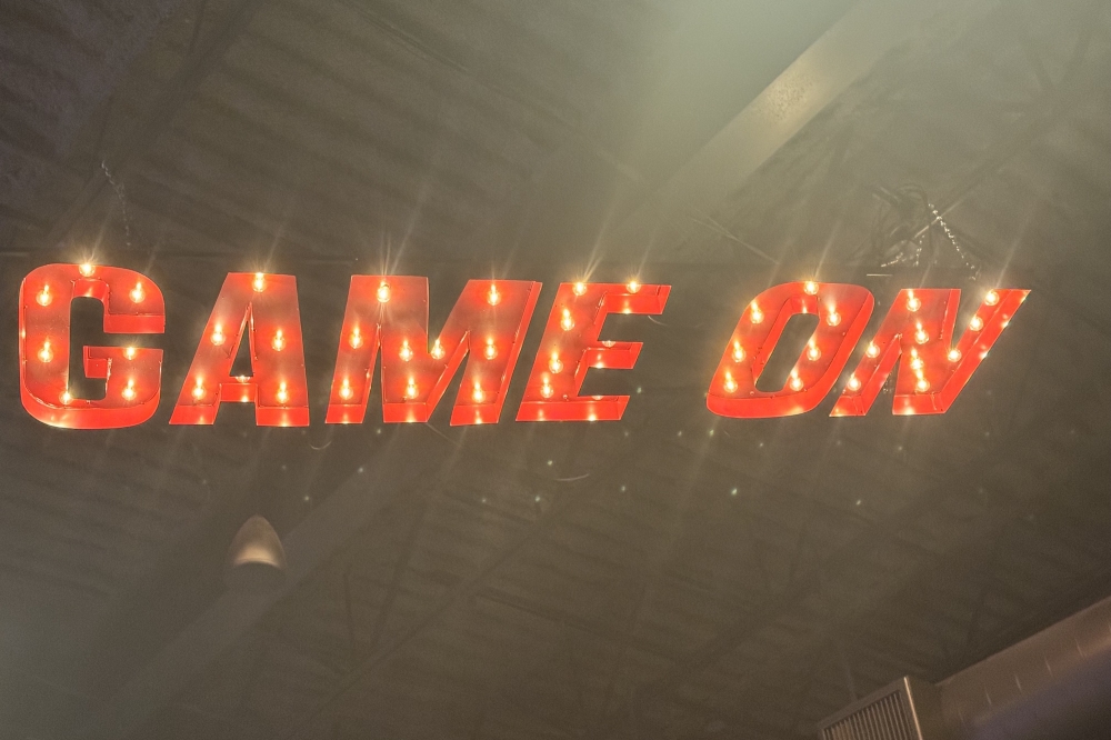 A light up sign on the ceiling that says "Game On"