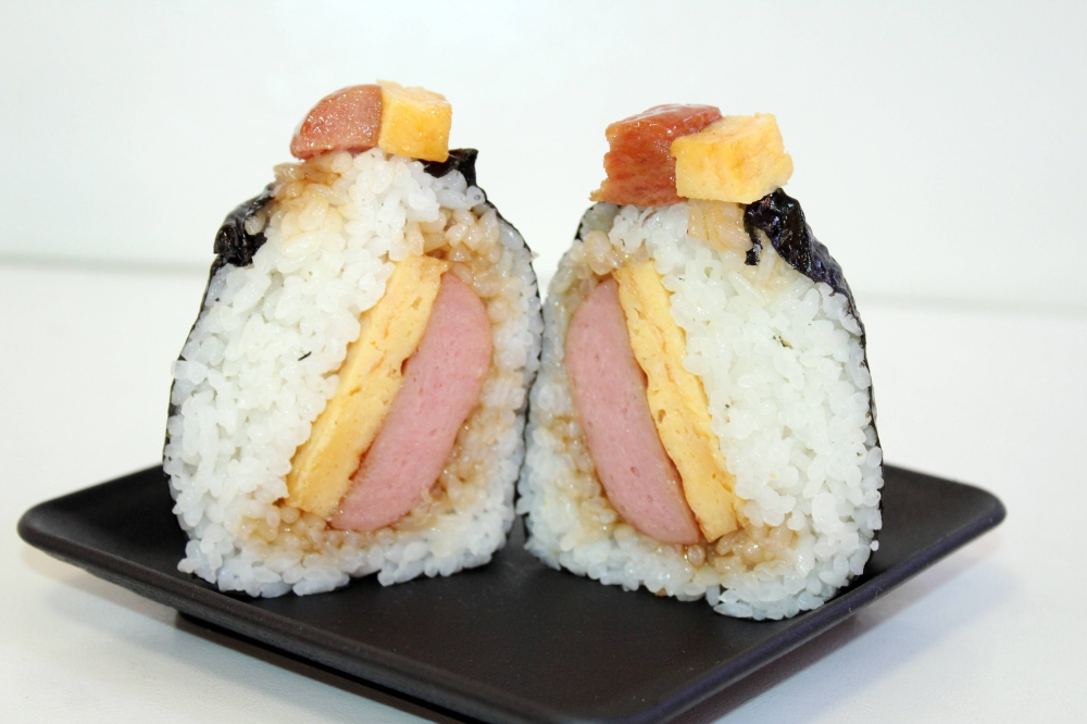 Onigiri cut in half showing rice, spam and eggs.