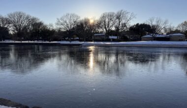 a large park lake with a thin layer of ice on the top