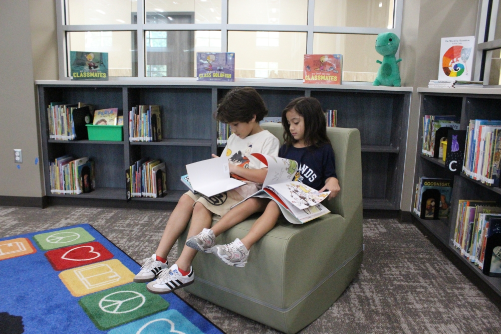 Third grader Christopher Garcia and first grader Gianna Garcia, siblings, enjoy their favorite books in the library at New Caney ISD's Highlands Elementary School. (Emily Lincke/Community Impact)