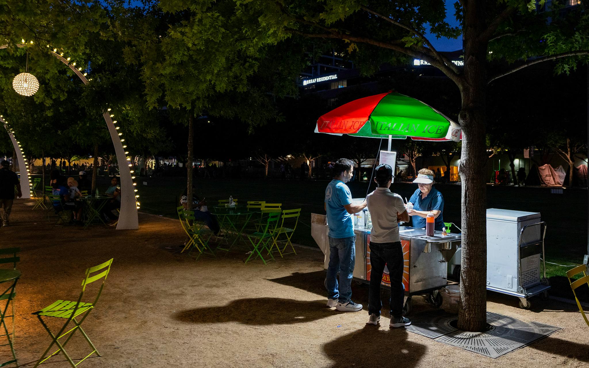 May 10 8:41 P.M. David Carmona (left) buys Italian ice from a stand with his son Salvador Salinas, 13, in Klyde Warren Park in downtown Dallas.