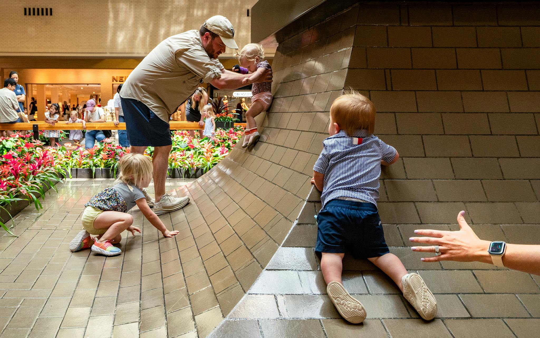 May 31 11:22 A.M. Bailey Burrus, 31, plays with his daughters Joan, 2, (right) and Eliza, 4 on the famous curved brick planters outside Neiman Marcus in NorthPark Center as 1-year-old Louis Schultz looks on. Burrus’ wife Abigail, not pictured, said, “It’s like full circle for me, because I grew up in Dallas, and all my life, I would run up and down these with my siblings.”