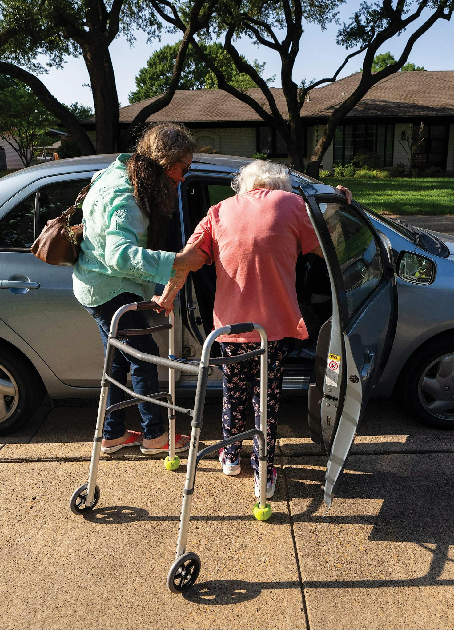 May 31 5:59 P.M. A woman helping her mother into her car on Heatherknoll Drive, in far North Dallas. The woman, a painter, shares caregiving responsibilities with her sister.
