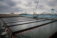 As construction continues in Plant 3, water flows through a sedimentation basin at the North...