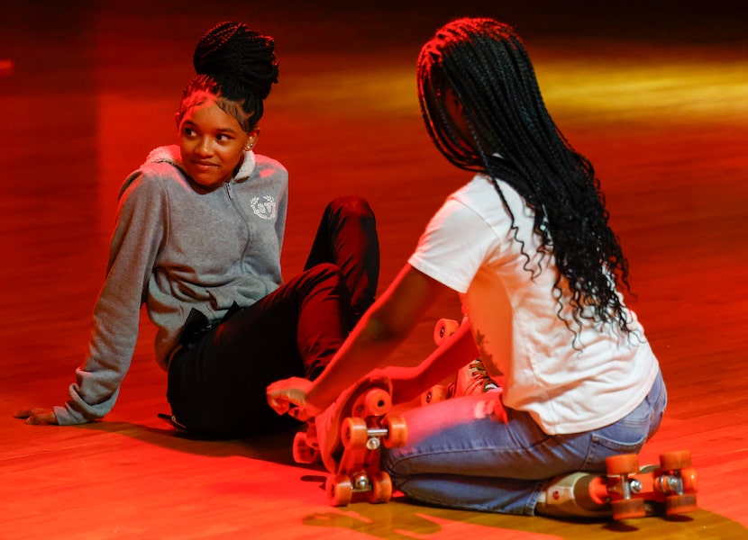 Ced’niya Shaw, 10 (right), ties the roller skates of Arnasia Bradley, 12, as they skate...