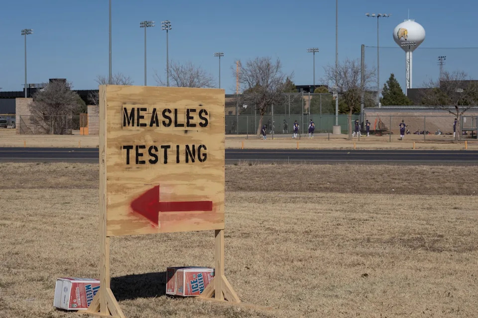 Jan Sonnenmair/Getty Images - PHOTO: Signs point the way to measles testing in the parking lot of the Seminole Hospital District across from Wigwam Stadium, Feb. 27, 2025, in Seminole, Texas.