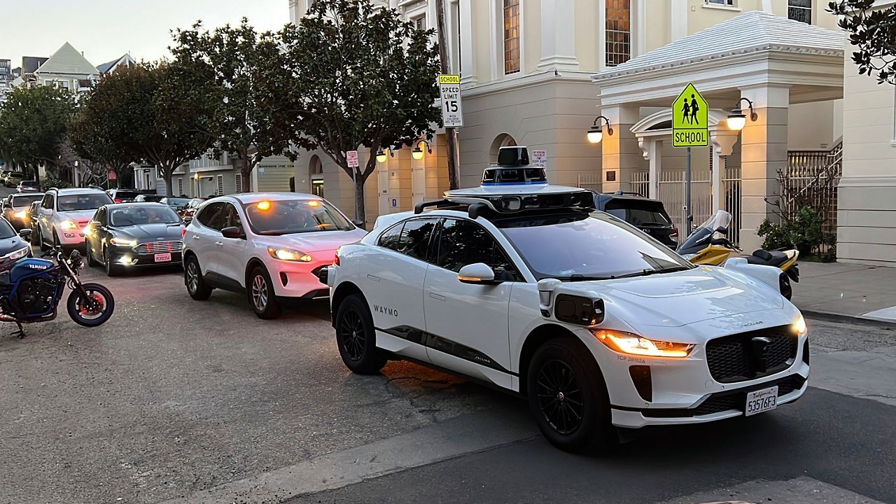 A Waymo driverless taxi stops on a street in San Francisco for several minutes because the back door was not completely shut, while traffic backs up behind it, on Feb. 15, 2023. (AP Photo/Terry Chea)