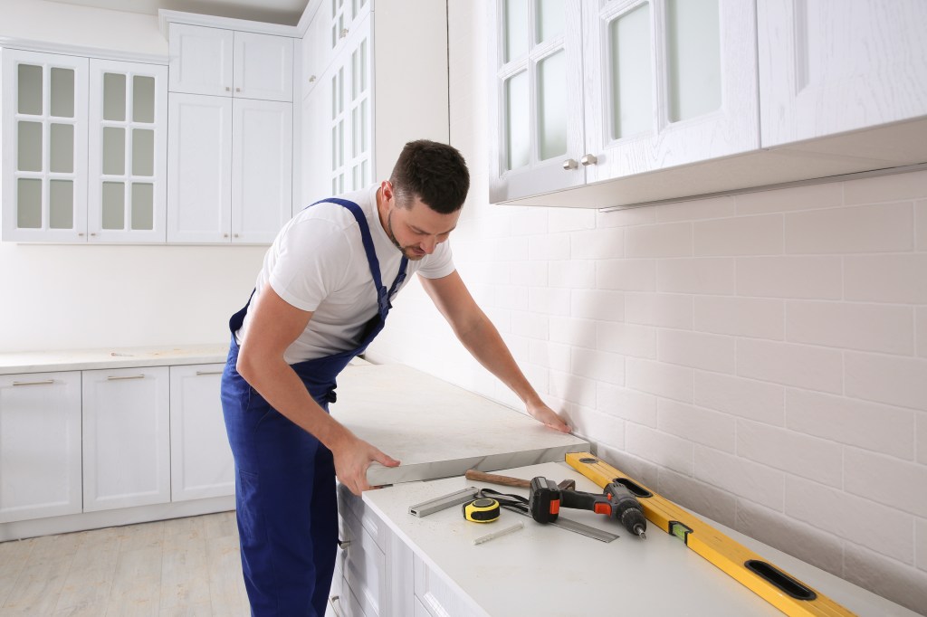 Worker installing a new countertop in a modern kitchen.