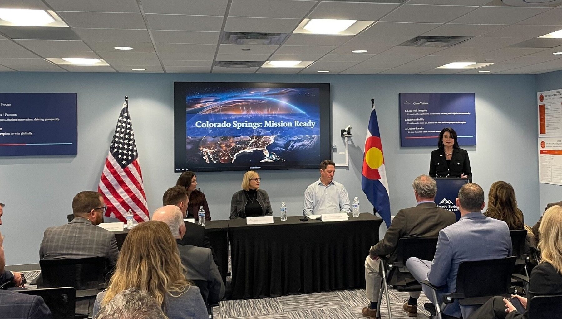 People sit in a audience facing a panel of city officials.
