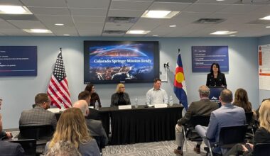 People sit in a audience facing a panel of city officials.
