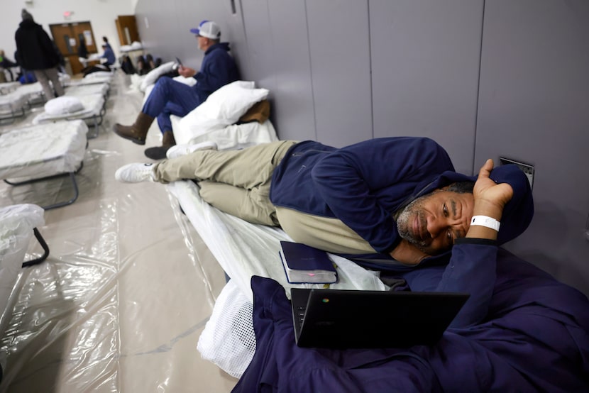 With his Bible and laptop, Chris Eddings, an unhoused client, watches a movie on his cot at...