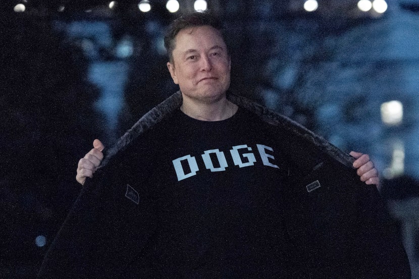 FILE - Elon Musk flashes his T-shirt that reads "DOGE" to the media as he walks on South...