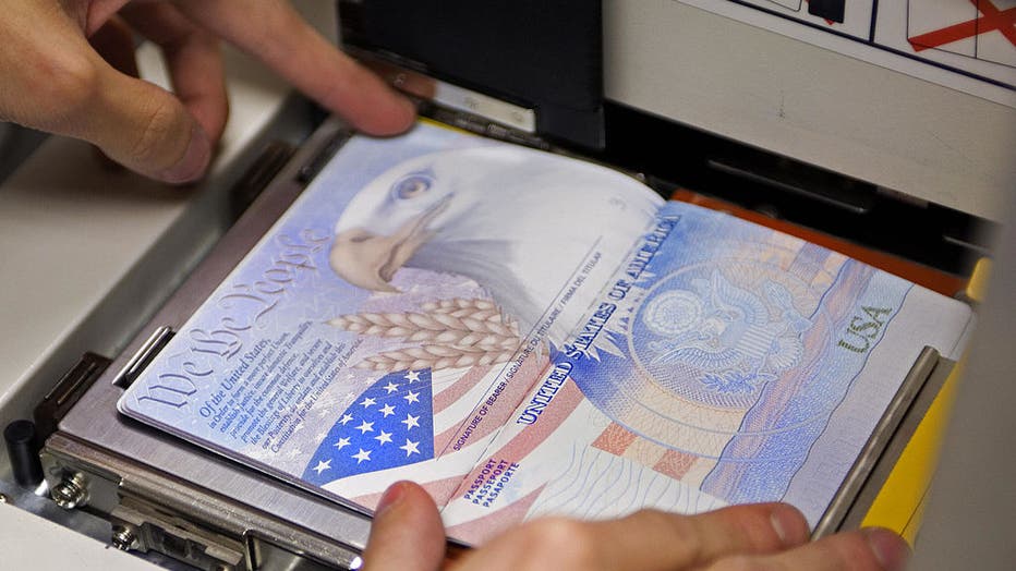 FILE IMAGE - A U.S. government official with the State Department's Passport Services places a new blank US Passport with an embedded electronic chip into the "book printer," entering personal data and the photograph. (Credit: PAUL J. RICHARDS/AFP via Getty Images)