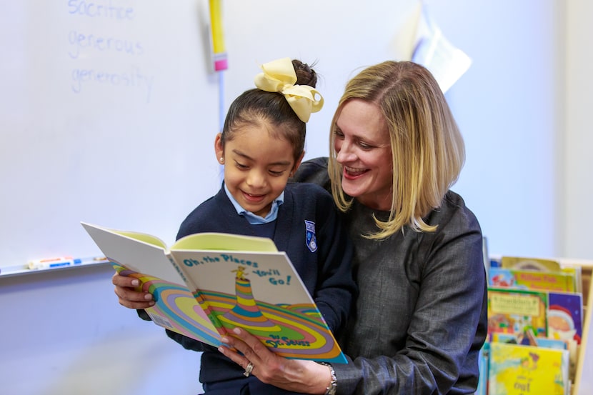 A woman smiles and reads to a child from the Dr. Seuss book "Oh the Places You'll Go"