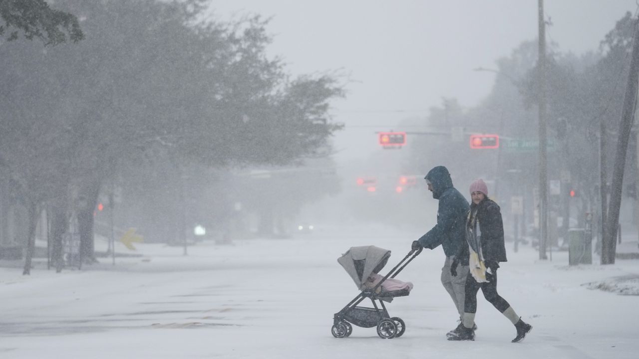 People take a walk in the neighborhood Tuesday, Jan. 21, 2025, in Houston. (AP Photo/Ashley Landis)