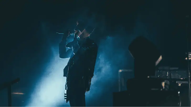 Music artist performing live on stage with dramatic lighting, capturing the essence of the music industry and concert experience.